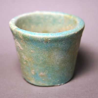 An Egyptian Blue glazed faience cup with contents, Dynasty 26, 664-525 BC